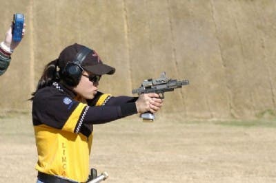A young female shooter using a heavily modified 1911 in a contemporary shooting competition.