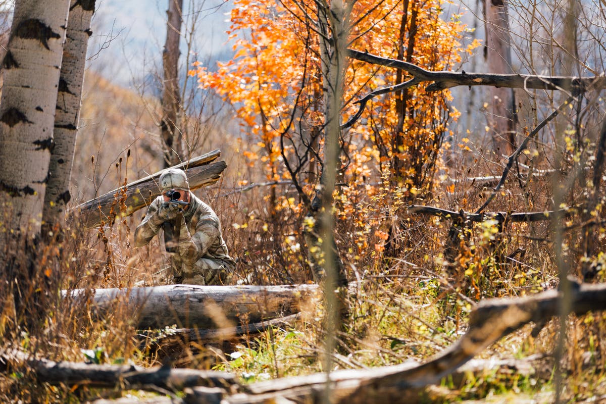 Hunter wearing A-Tacs camo aiming an  X-Bolt rifle in quaking aspen trees